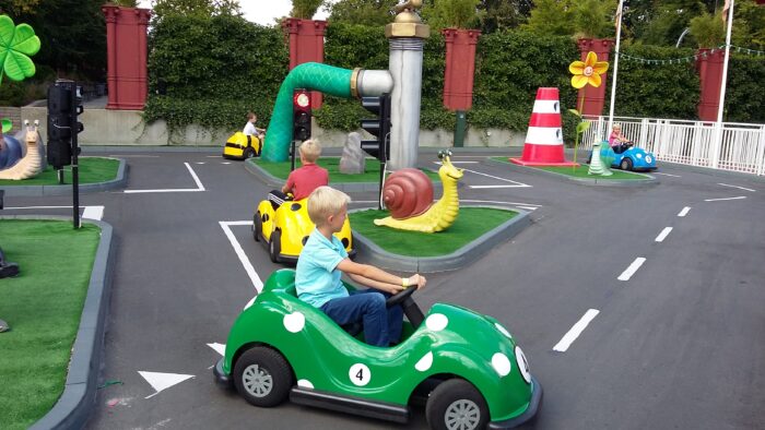 A child driving a green toy car