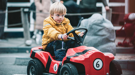 boy driving a red children's car