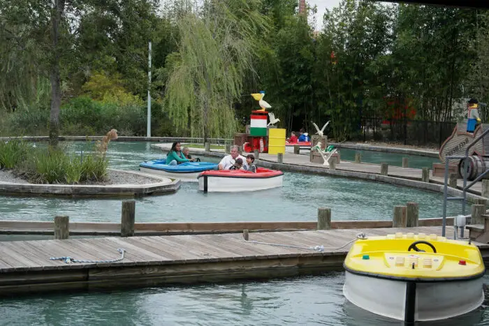 Three Lego boats at Legoland, driven by adults and children. The boats are manufactured by SBI Sweden in Jönköping