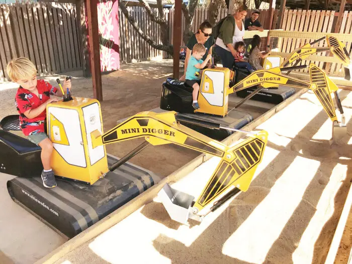 Children and parents participating in a digging activity with a fully operational older Mini Digger, manufactured by SBI Sweden in Jönköping