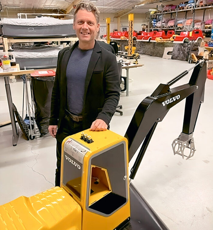 Markus Johnson CEO from SBI Sweden, standing next to a Volvo mini digger at the assembly facility in Jönköping, highlighting the connection between innovative machinery and skilled personnel