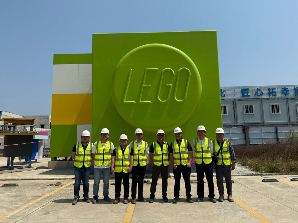 a group of people in reflective vests and helmets infront of a big green Lego