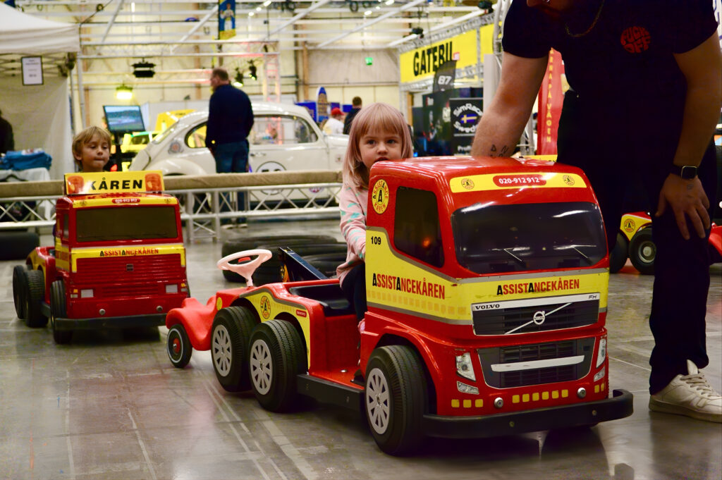 children driving mini tow trucks on a indoor track