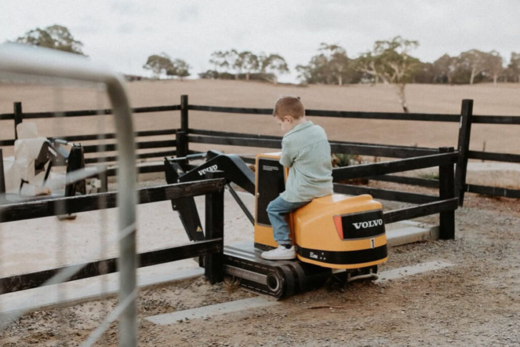 a boy on a mini excavator digging in the sand at hahndorf farm barn in Adelaide, Australia