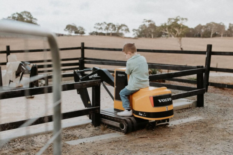 a boy on a mini excavator digging in the sand at hahndorf farm barn in Adelaide, Australia