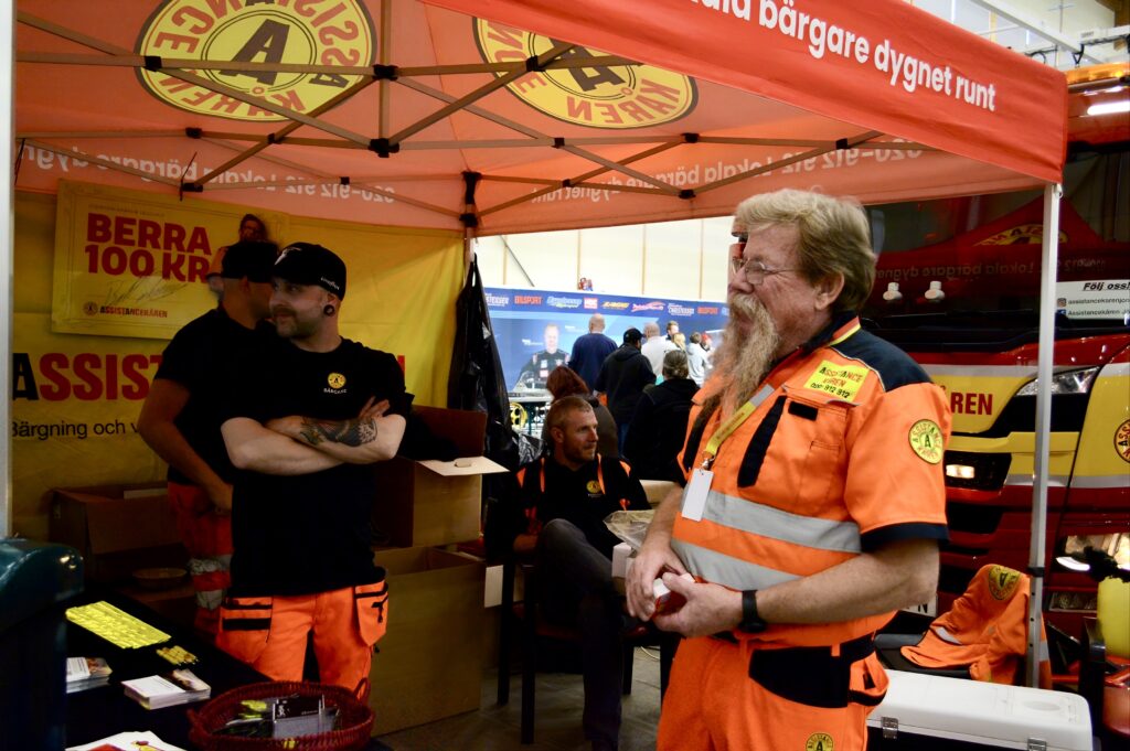 men from assistancekåren talking in a booth at a fair